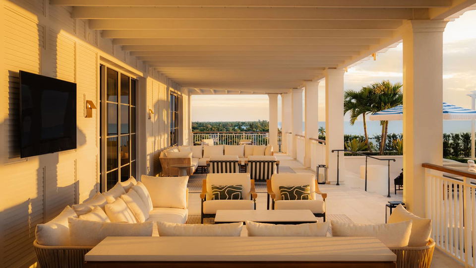A luxury hotel suite terrace with white furniture, exposed beam ceiling, Gulf views, and architectural details consistent with coastal resort design;