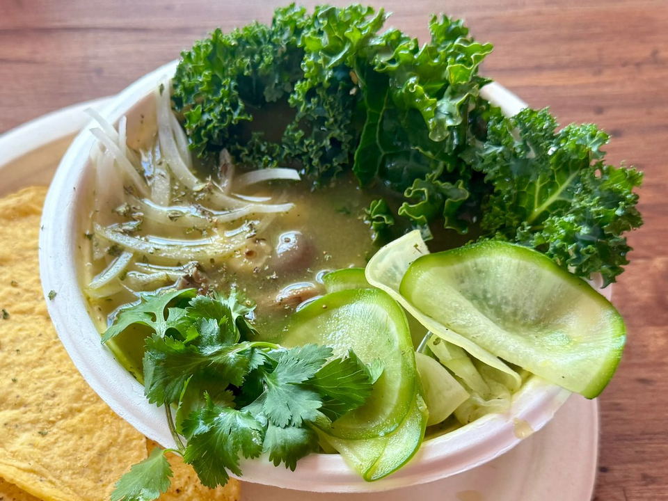 Seedy's pozole bowl, garnished with kale, cucumber, and cilantro, served with a corn tortilla.