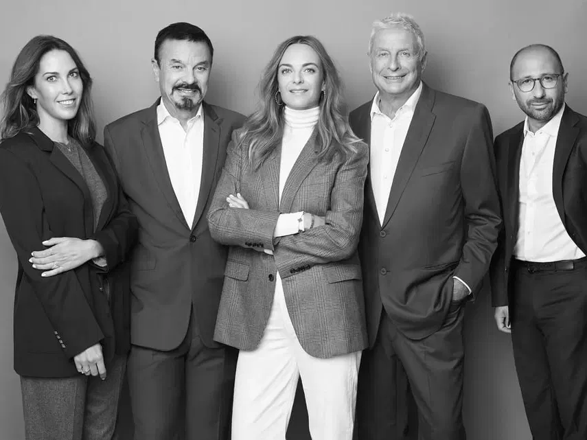 Black and white group portrait of five Clarins Group executives standing together, three women and two men in business attire.