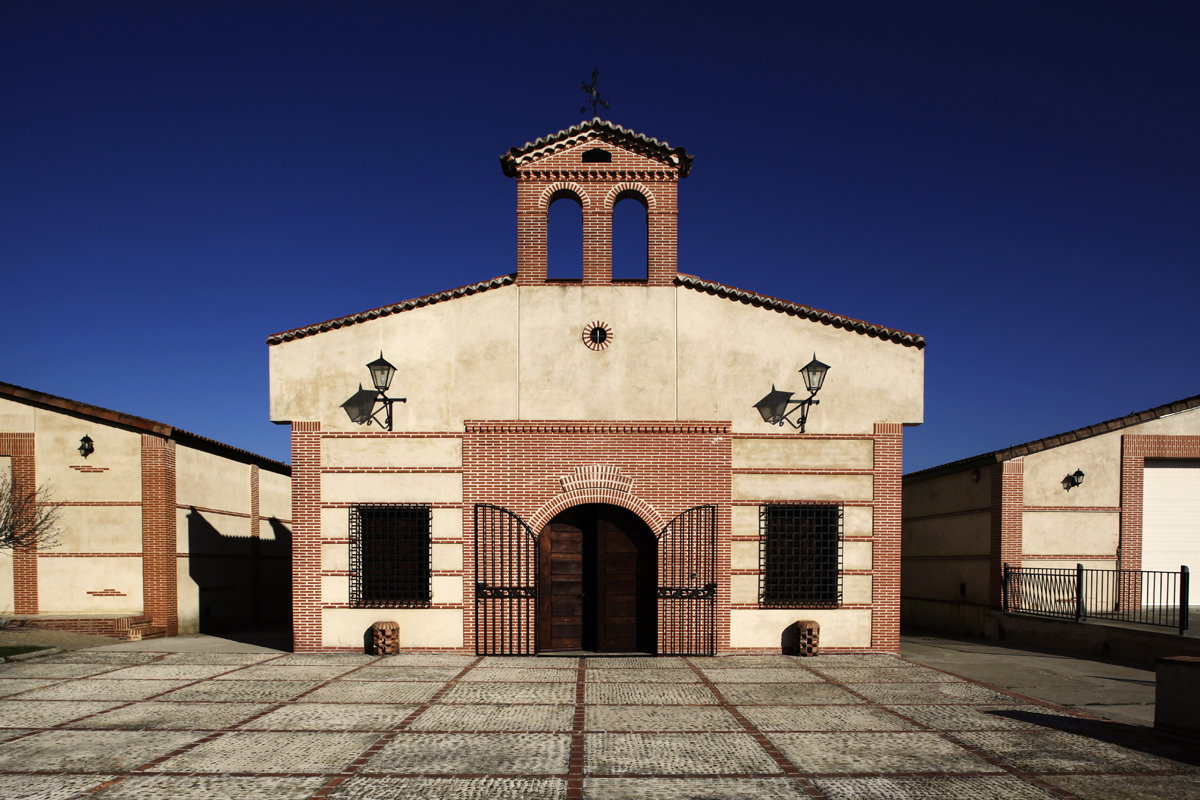 A Spanish winery building with distinctive brick and stucco architecture featuring a bell tower, arched entrance, and courtyard; the source page expli