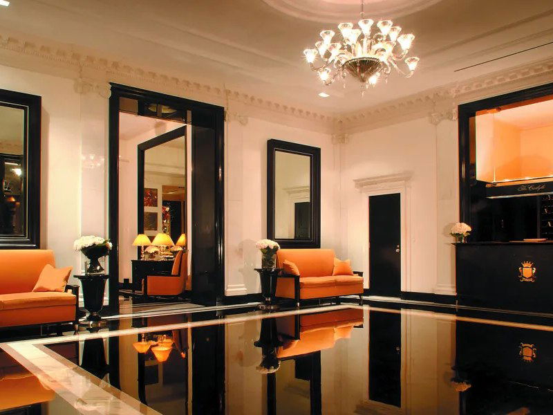The Carlyle, A Rosewood Hotel lobby exudes Upper East Side residential elegance with polished floors and orange sofas.