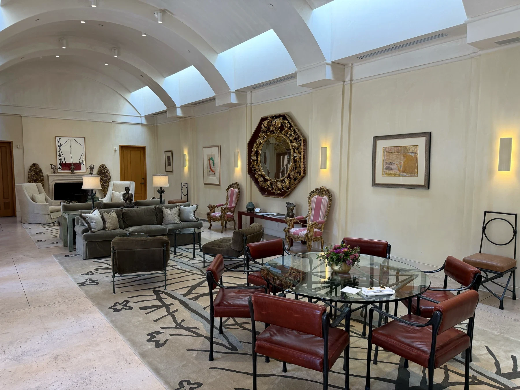 Opus One Salon with red leather chairs, art, antiques and an ornate mirror beneath skylights