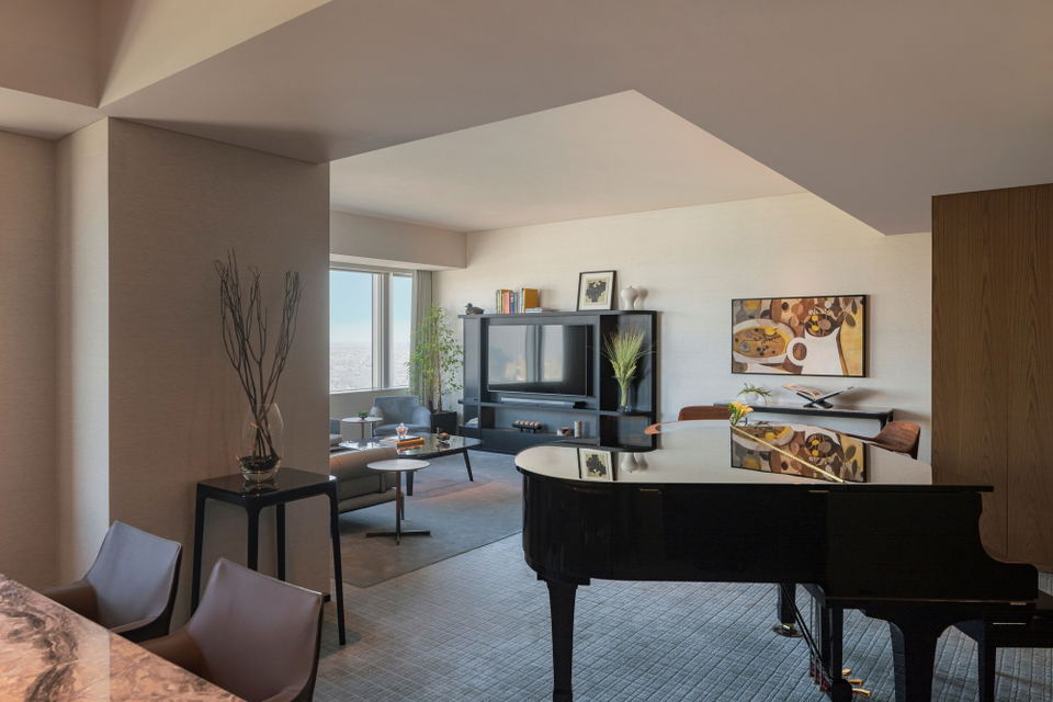 The Diplomat Suite living room at Park Hyatt Tokyo, with a grand piano, lounge seating, and city views.