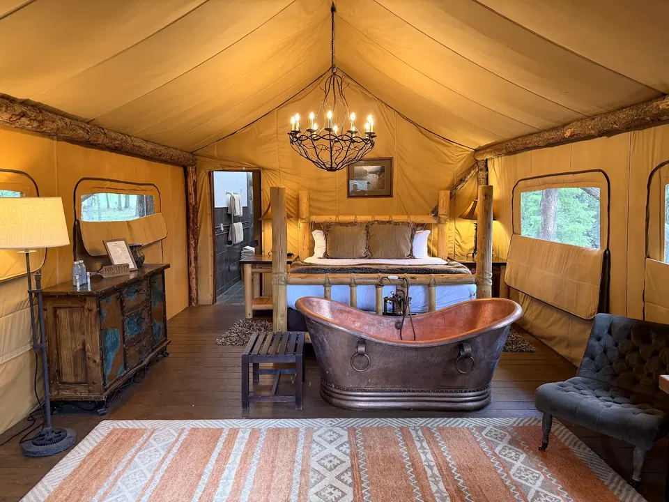 Copper soaking tub and king bed inside a Cliffside Camp glamping tent