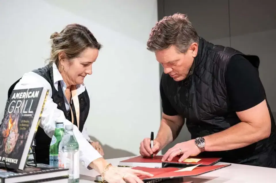 An author signs a cookbook for a guest at the 2025 Food and Wine Classic in Charleston