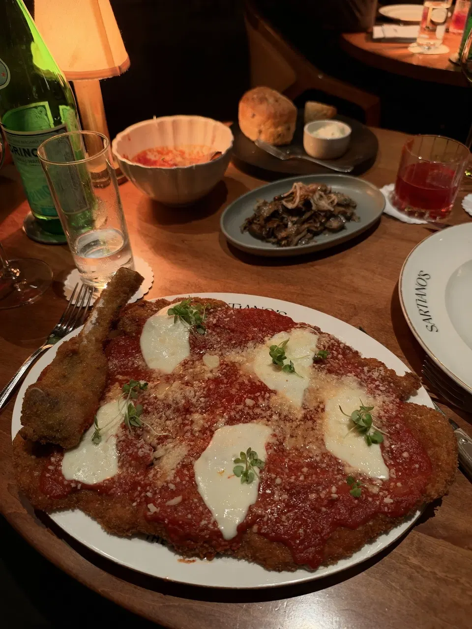 The generous bone-in veal parmigiana, with mushrooms on the table.