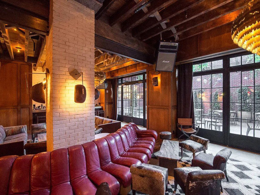 Dirty French: A cozy interior with red leather sofas, exposed beams, and a view of the patio.