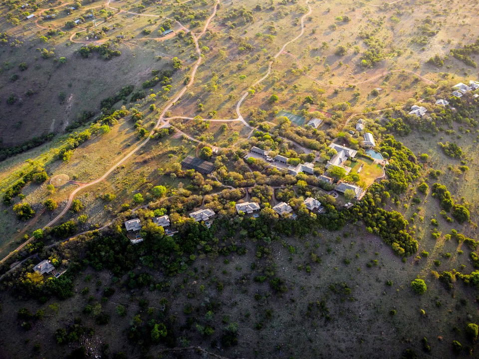Singita Sasakwa Lodge: An aerial view of a luxury safari lodge complex and winding dirt tracks in the savanna.