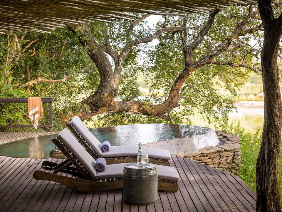 Singita Boulders Lodge: A private plunge pool on a wooden deck with lounge chairs and a river view.