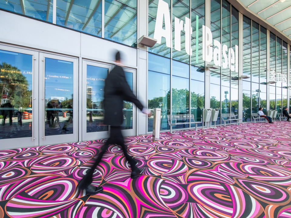 Art Basel welcomes visitors to its Miami Beach Convention Center entrance, featuring a vibrant floor installation.