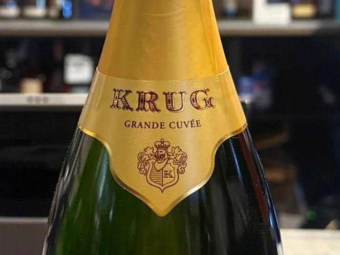 A bottle of Krug Grande Cuvée 162ème Édition Brut Champagne on a wooden surface in a retail shop.