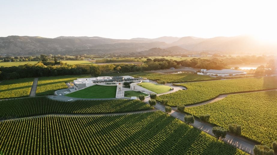 Opus One winery, nestled amidst its 170-acre Oakville vineyard, bathed in the golden light of the setting sun.
