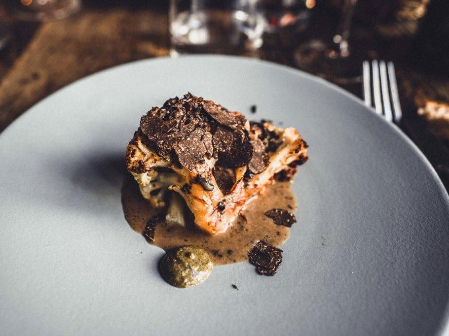 A precisely plated fine-dining course from Septime, featuring roasted cauliflower topped with shaved black truffle and a creamy truffle sauce on a
