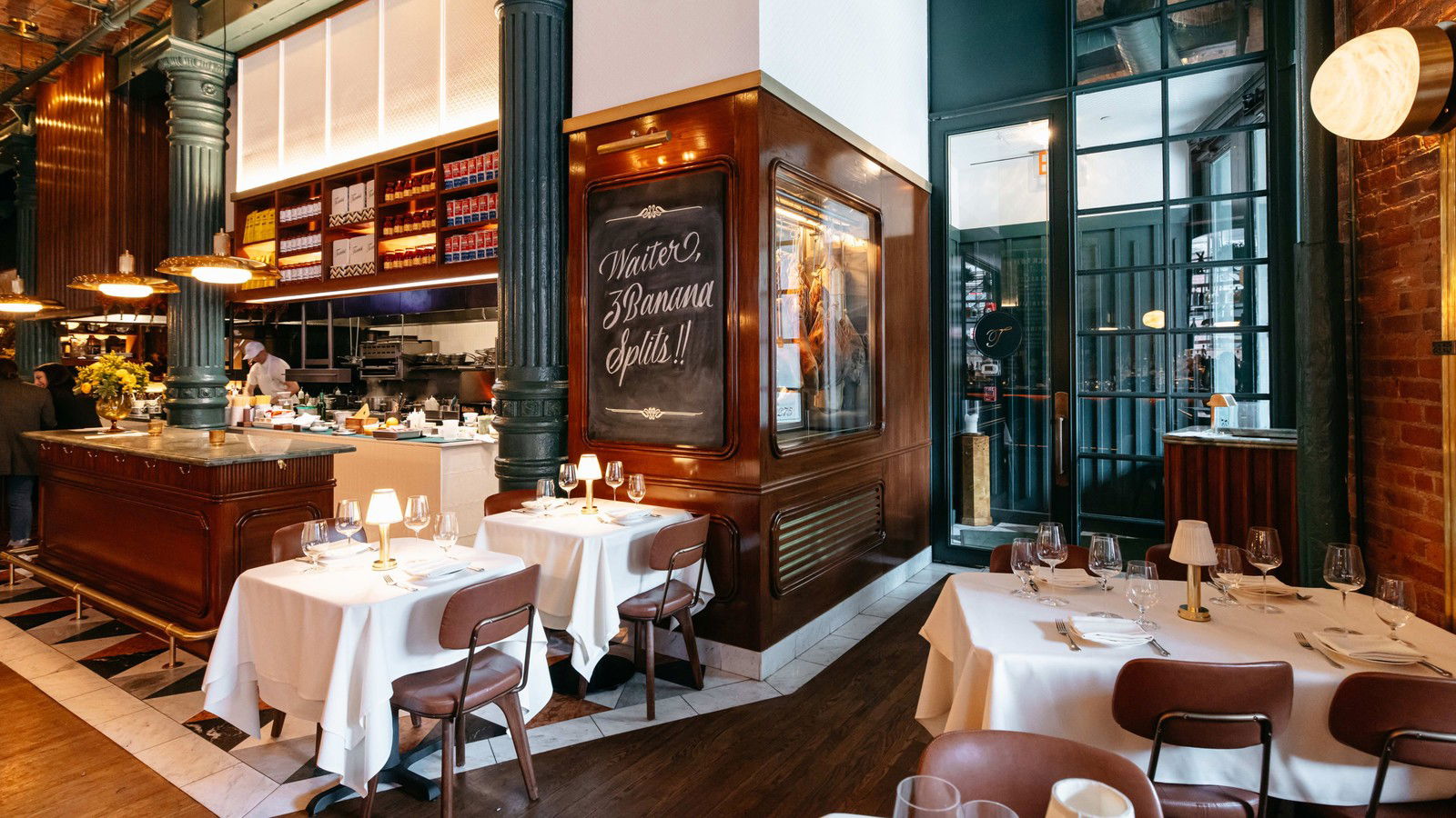 The Torrisi dining room, intimate and warmly lit, with tables set for service and a playful chalkboard message.