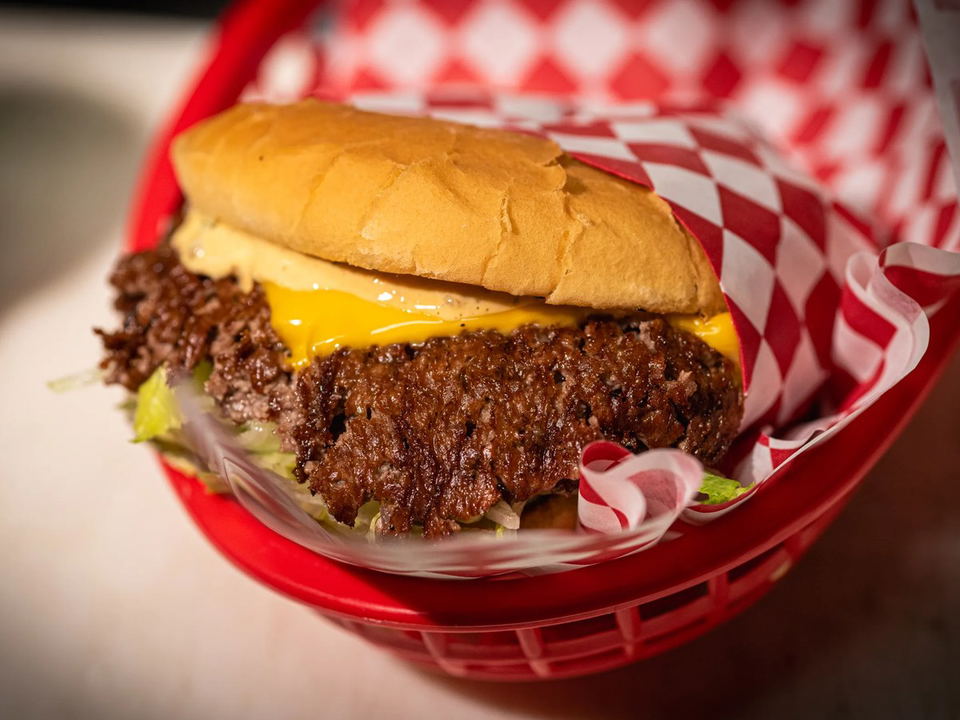 Sure Shot smash burger with double-stacked patties on checkered paper, showing the crispy edges and classic presentation.