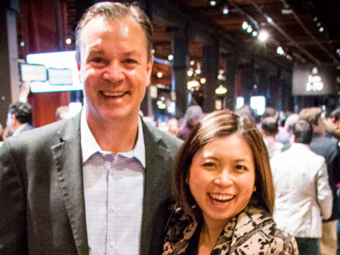 Two smiling individuals at a crowded event venue.