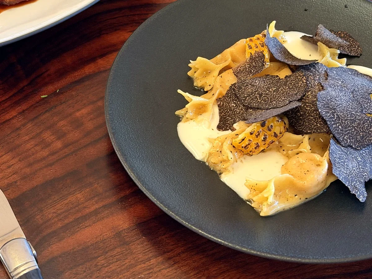 Sweet corn caramelle with shaved black truffle beside other shared courses at PRESS