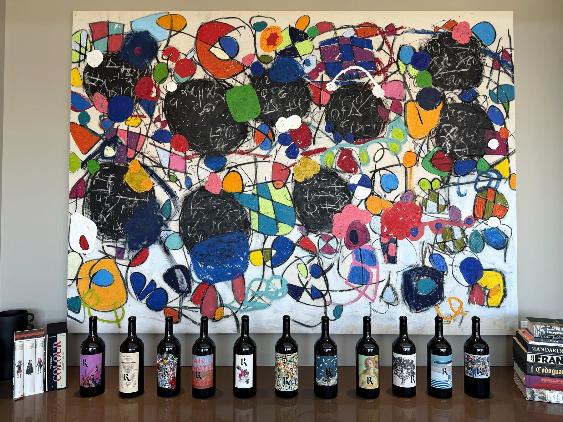 Realm Cellars bottle labels displayed beneath a colorful contemporary painting at Houyi