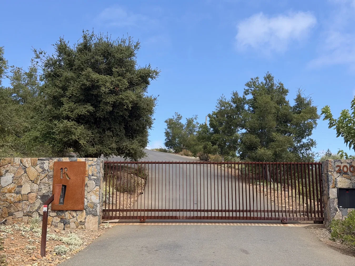 Weathered steel Realm R set into the stone gatepost at Houyi Estate