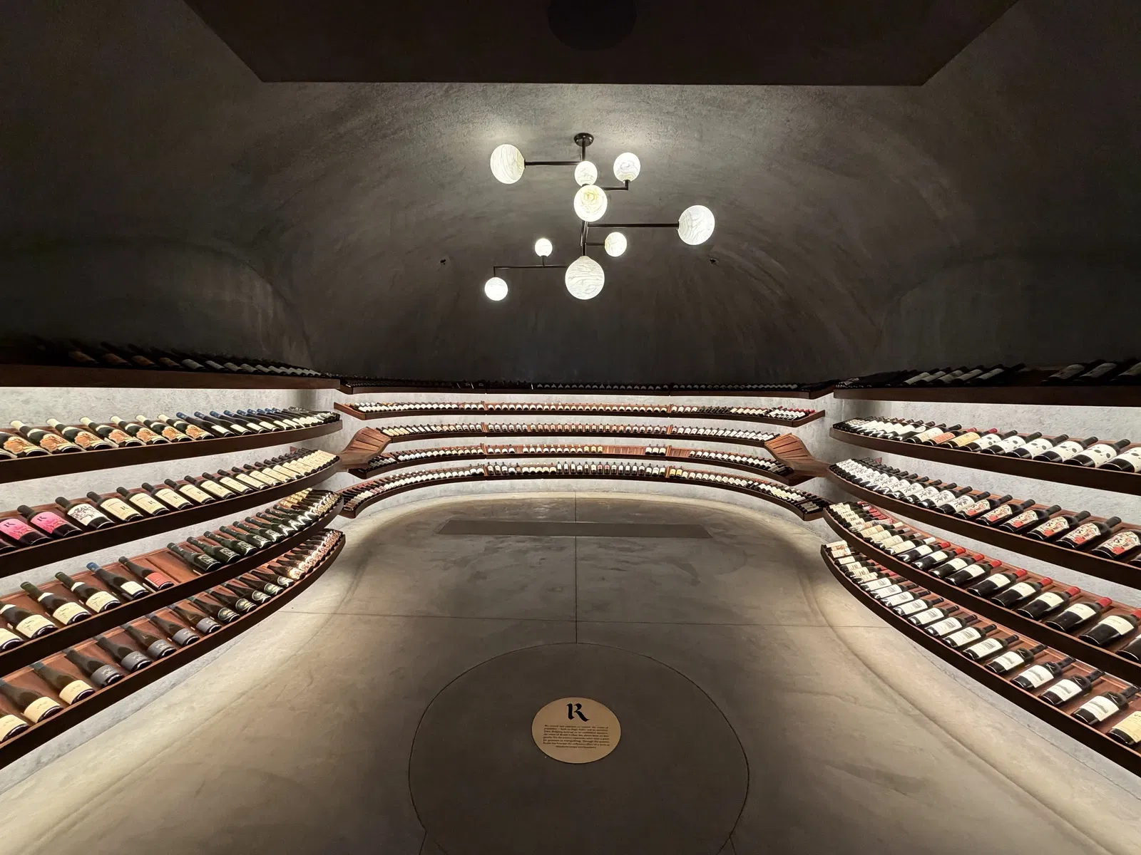 Curved rare-wine library with illuminated bottle shelves at Realm Houyi Estate