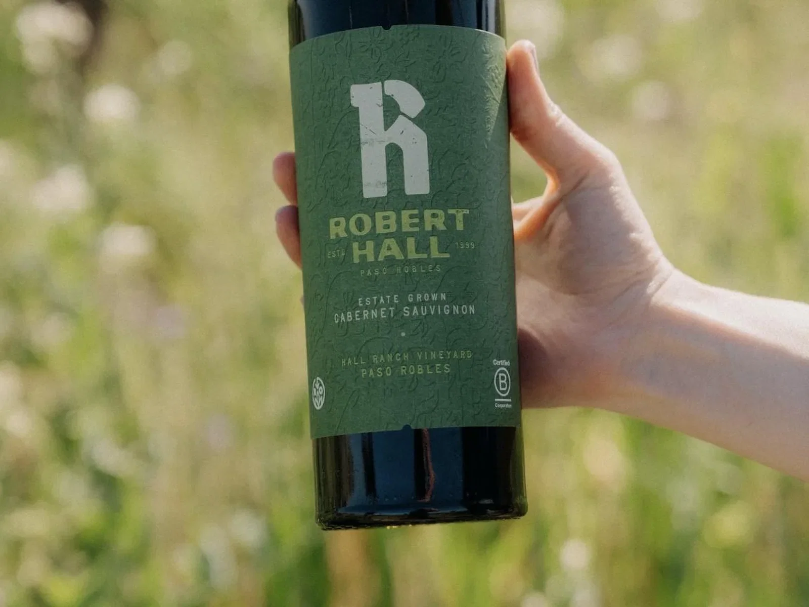 Bottle of Robert Hall Cabernet Sauvignon held against a green vineyard background.