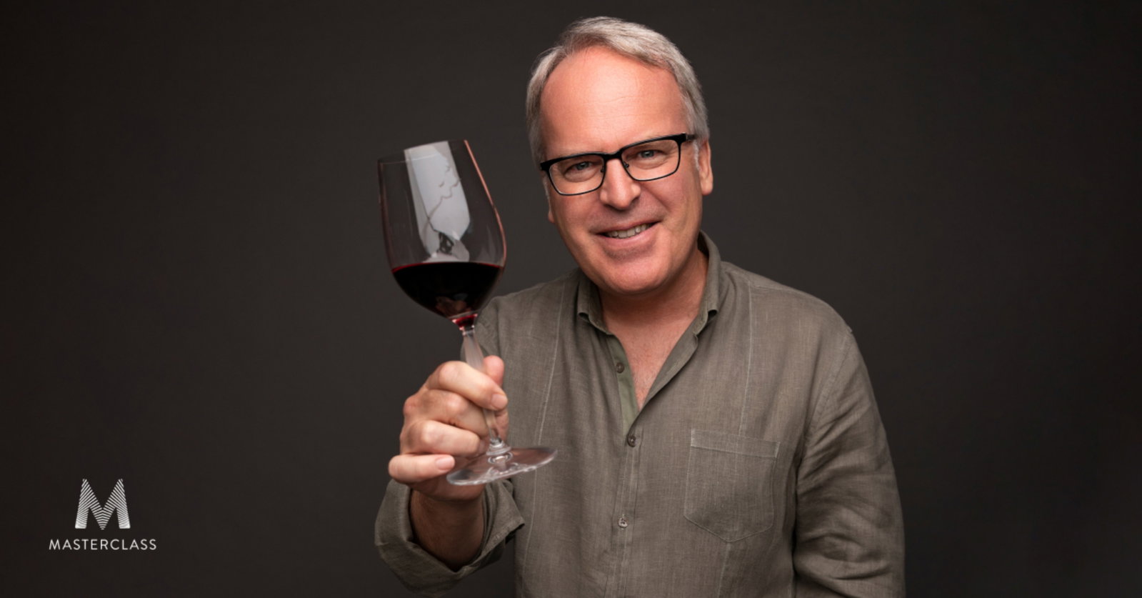 A man with gray hair and glasses holds a glass of red wine, smiling at the camera, with a Masterclass logo in the bottom left.