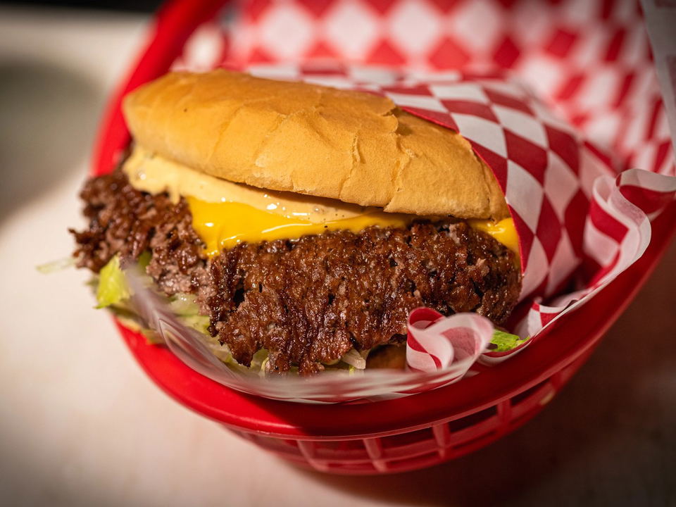 This double cheeseburger contradicts Sazanami's sushi focus, served in a red basket with checkered paper.