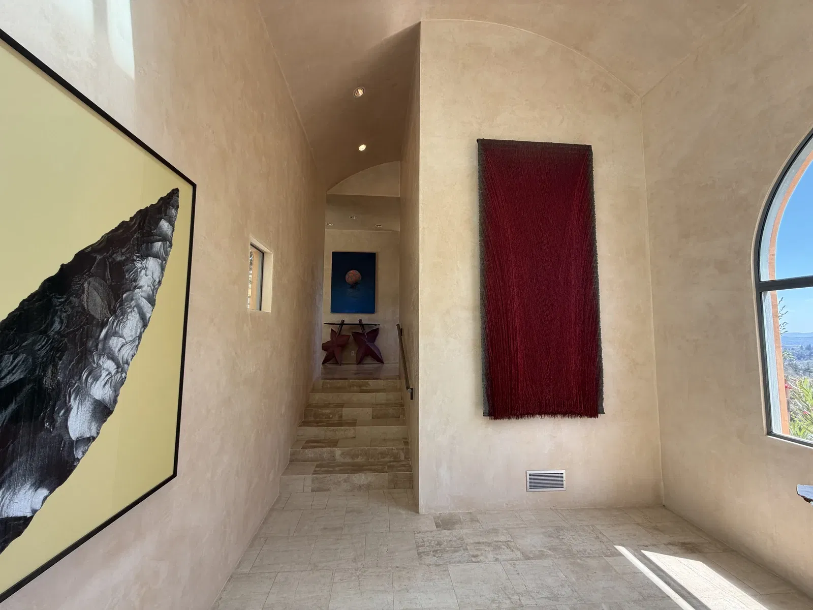 Pale stone entry hall with red textile and contemporary art at Seven Stones Estate