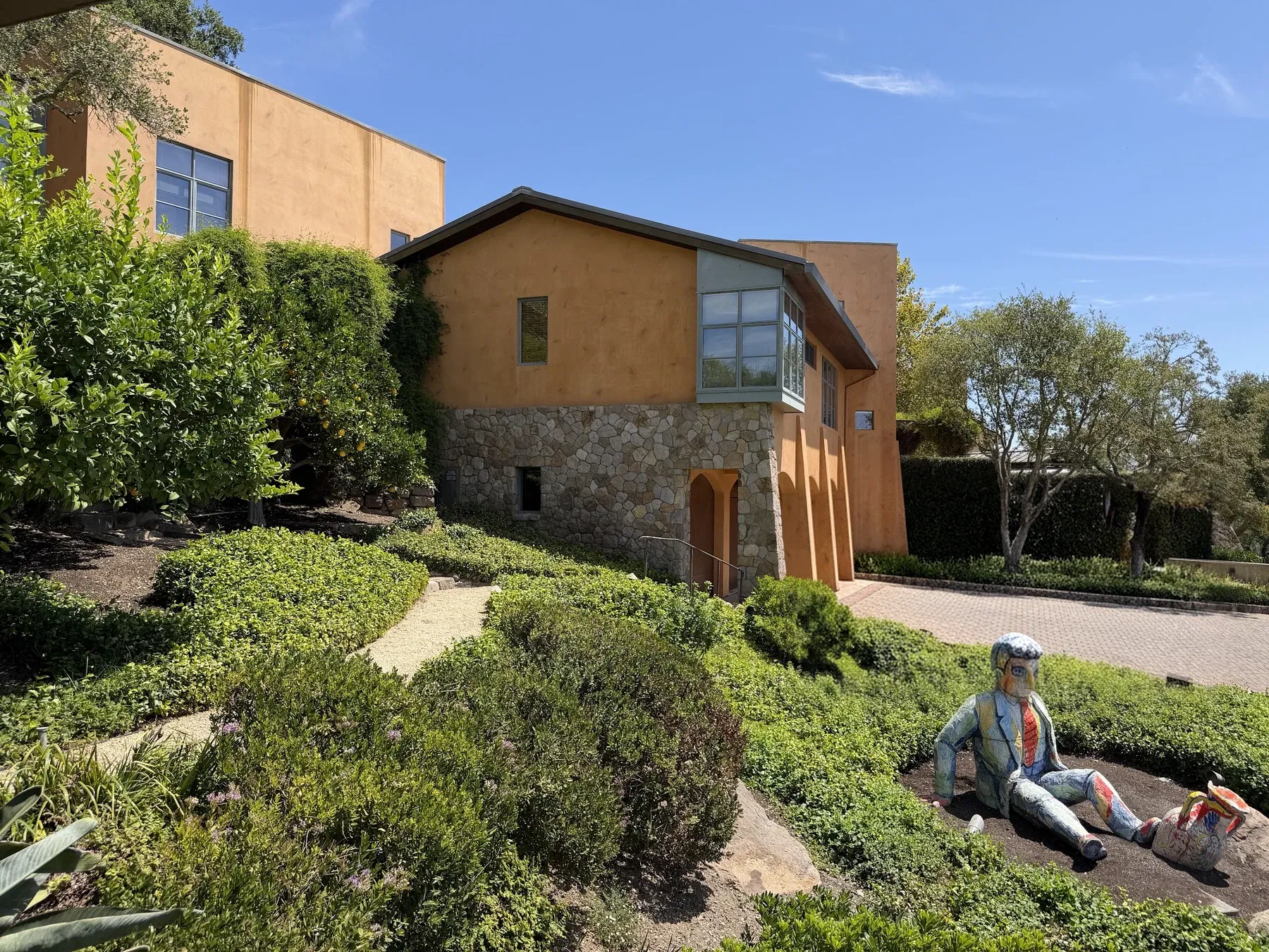 Terracotta walls and stone base of the Seven Stones residence above its clipped garden