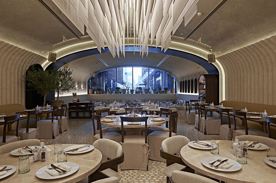 Avli by Tashas (DIFC) offers a spacious dining area with a large, arched window overlooking city views.