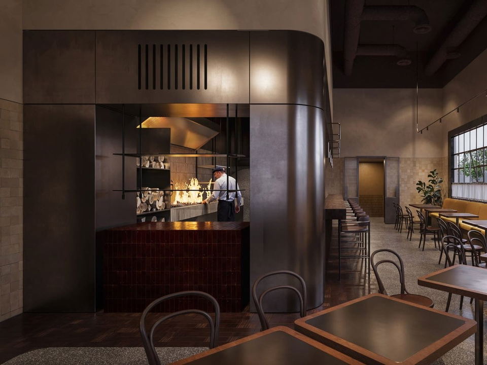 An open kitchen at Window restaurant in Alserkal Avenue, Dubai, with a chef working at a wood-burning grill and stacked logs.