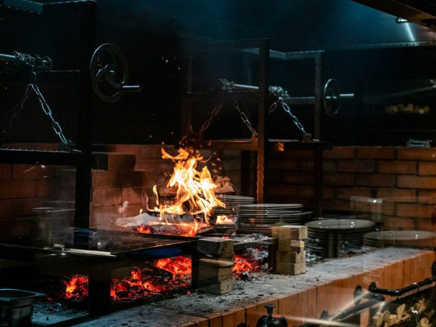 11 Woodfire (Dubai)'s open-fire cooking station, showcasing dramatic flames and glowing coals.