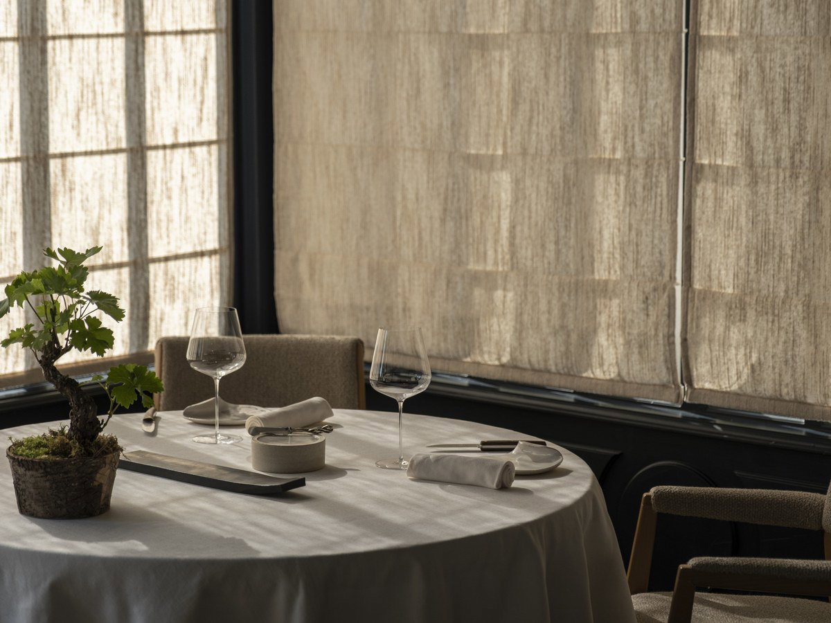 La Grand'Vigne offers an elegant dining experience, bathed in natural light filtering through sheer curtains.