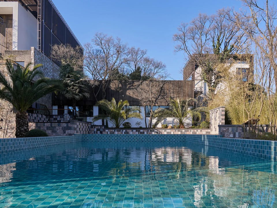 Songtsam Linka Kunming's outdoor lap pool, reflecting the dark timber and stone architecture.