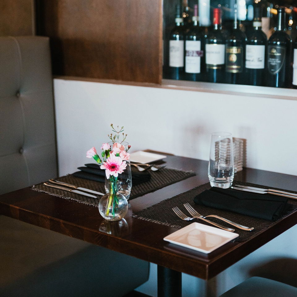 Mievè (La Brea) features a small vase of vibrant pink flowers on the table.