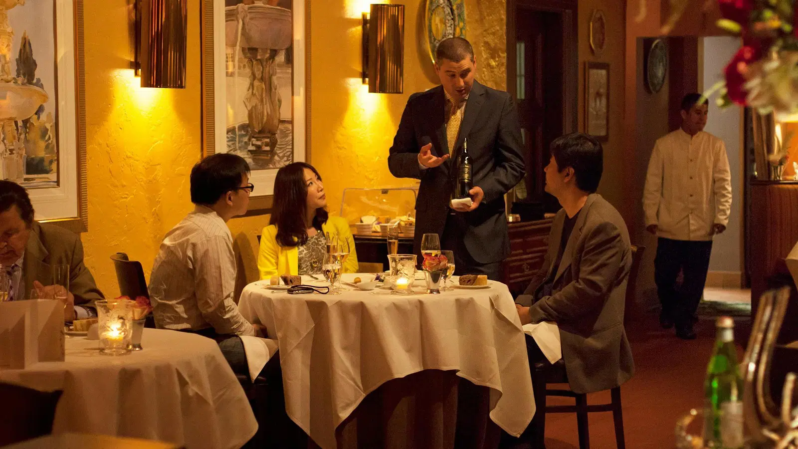 A sommelier presents a bottle of wine to guests at a fine dining restaurant.