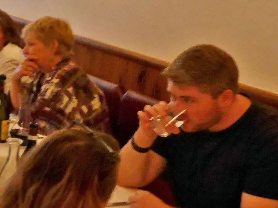 A busy dining room at I Sodi, with a mix of tables and bar seating filled with people eating and drinking.