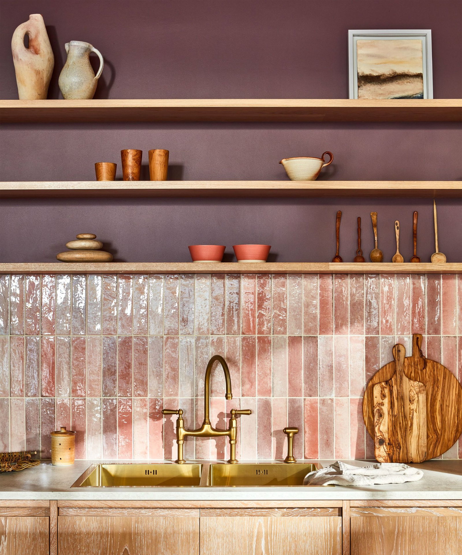 Aubergine's kitchen area gleams with elegant brass fixtures and a unique pink-hued tile backsplash.
