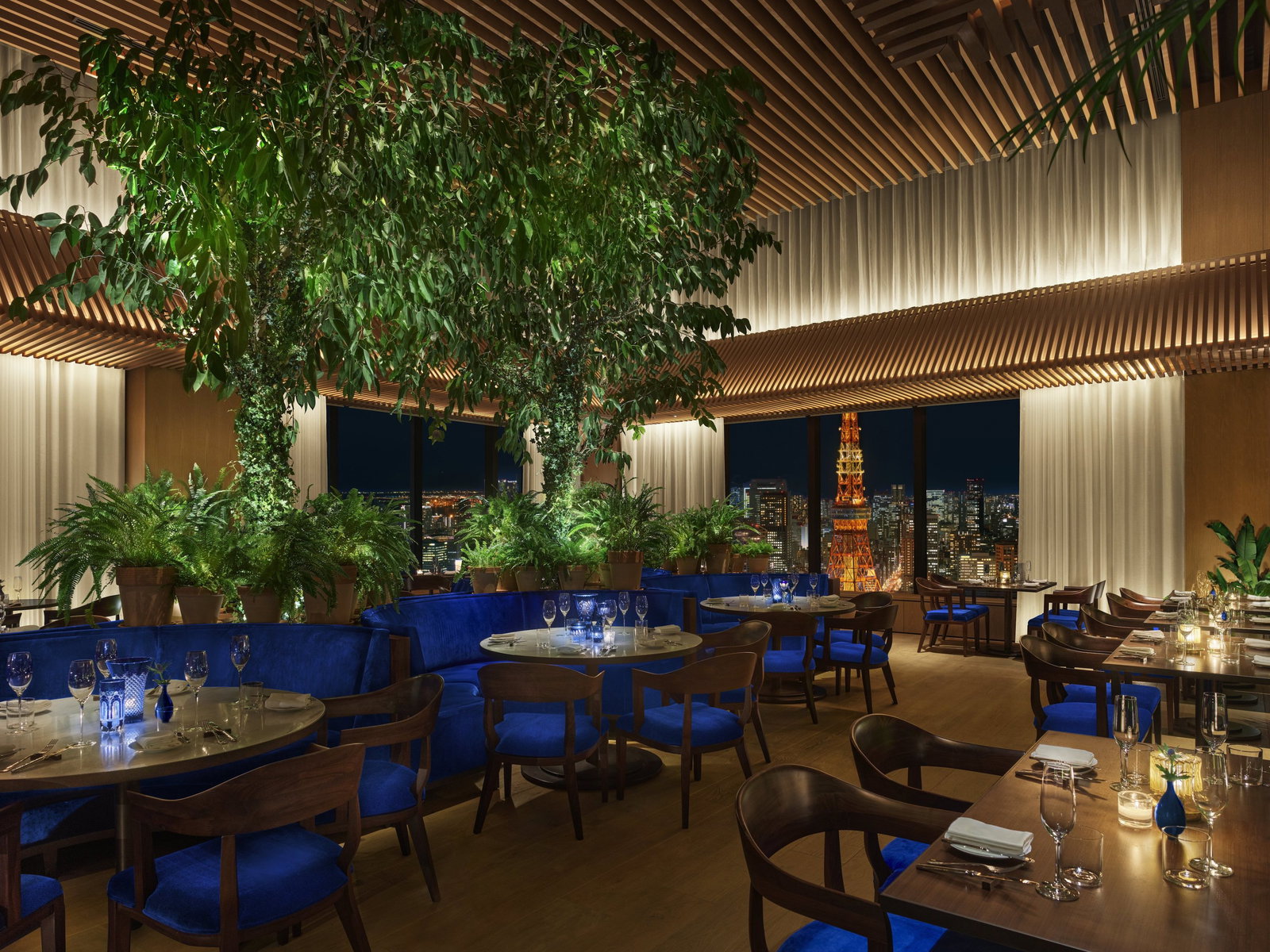 Den Tokyo offers a vibrant dining experience with lush greenery and stunning city views.