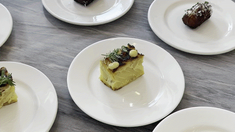 Multiple plated dishes on white plates showing what appears to be Tortilla Española (yellow layered egg dish with garnish) in the foreground and other