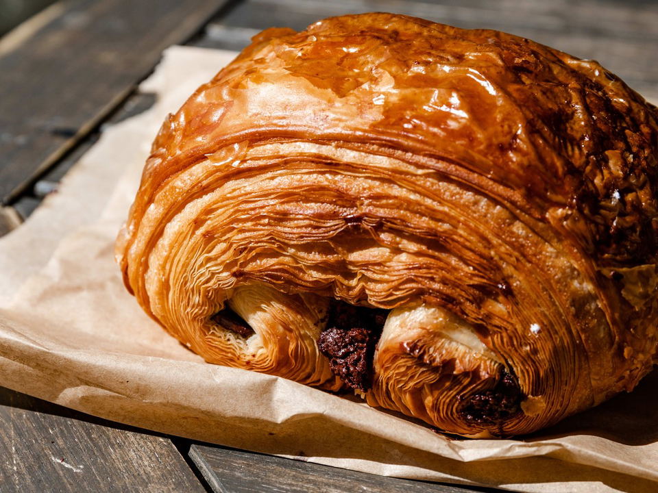 Wa-Iro's flaky, golden-brown laminated pastry with a dark filling, on parchment paper.
