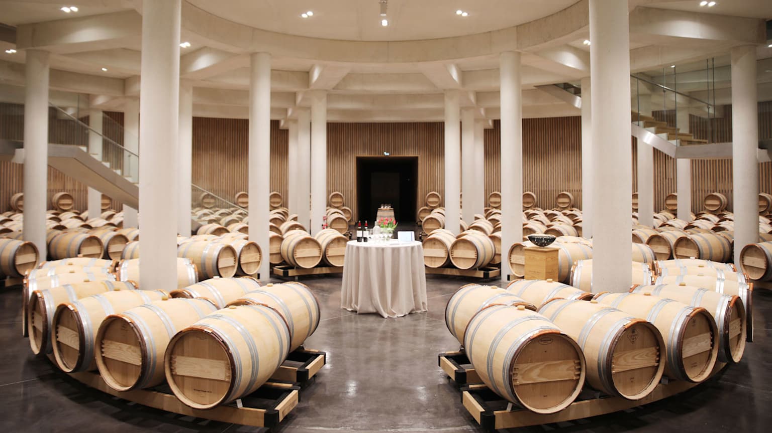 Bordeaux 2023 Vintage Summary features a grand hall filled with rows of light-colored oak barrels.