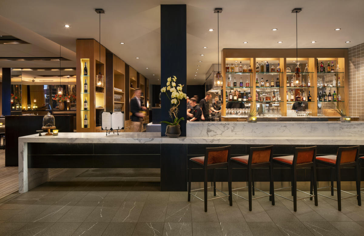 8. La Toque, Napa highlights illuminated wine bottles displayed in elegant wooden shelving.