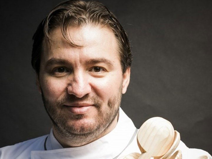 A chef in white chef's coat holding wooden spoons in a professional portrait; the source page explicitly names this as Chef Vítor Matos in an article