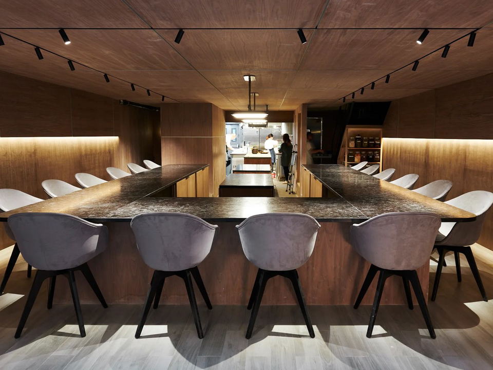 Atomix's sleek U-shaped counter and warm wood-paneled dining room create an atmosphere of anticipation.