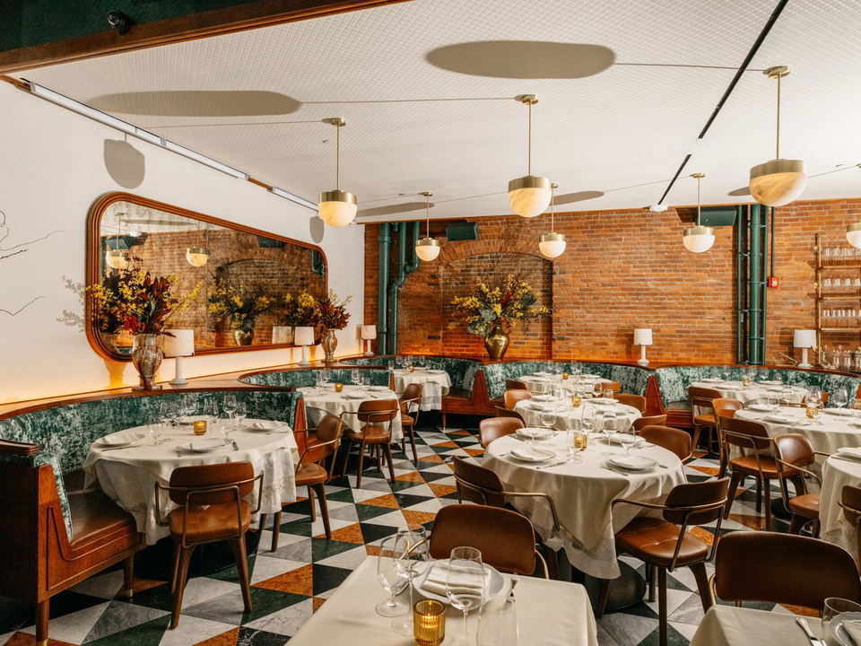 Elegant dining room with banquettes, tables, and brick walls