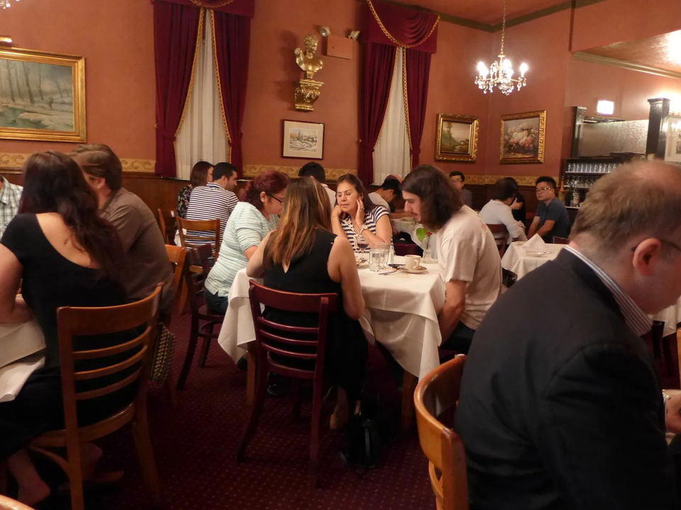 Diners seated at tables in a restaurant with red walls