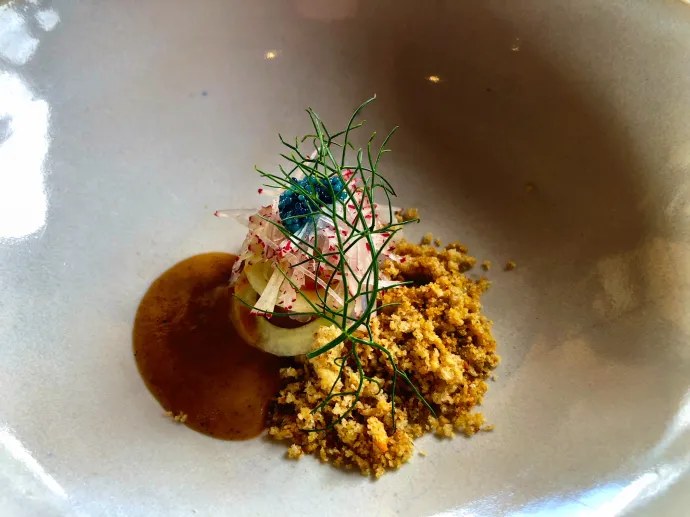 A fine-dining dish by Brendan Pratt featuring a central element with thinly sliced radish, fennel fronds, blue caviar, and a golden crumb.