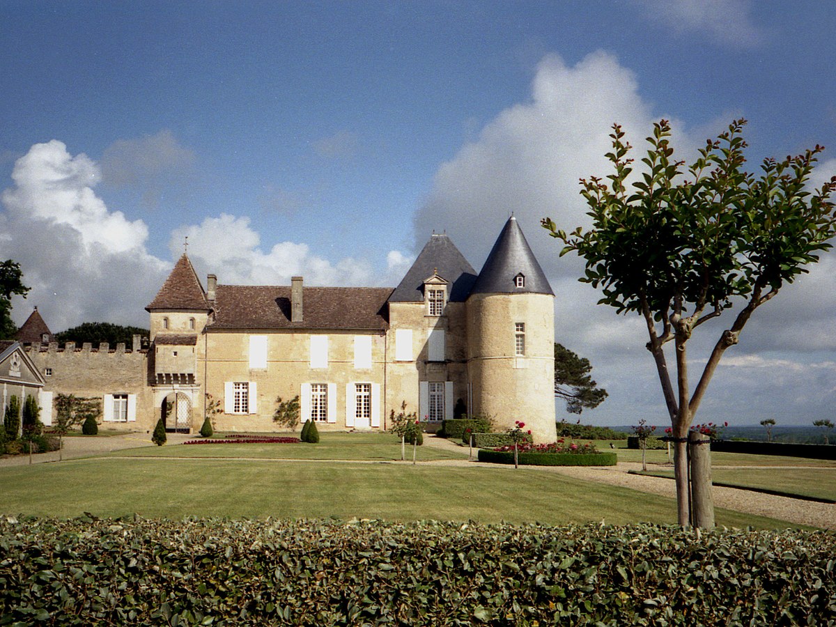 Château d'Yquem with a tree and manicured lawn under a cloudy sky
