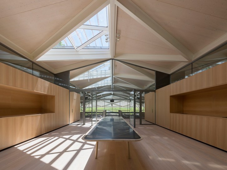 Interior of the Norman Foster-designed nouveau chai at Château Margaux, showing a light-filled timber-clad hall with a vaulted skylight roof, long